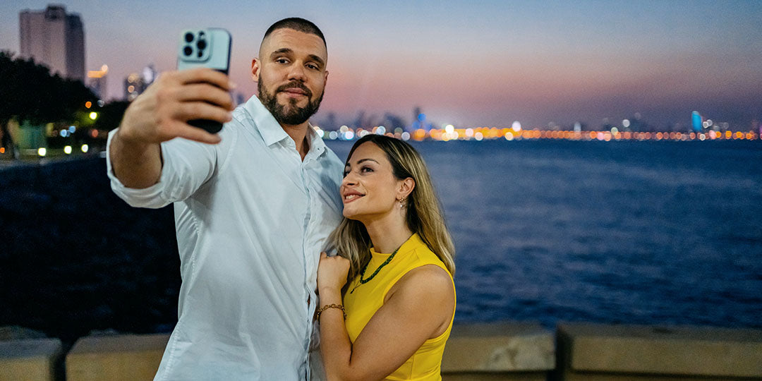 A couple is gathered to take a photo on a bridge in front of a fading sunset.